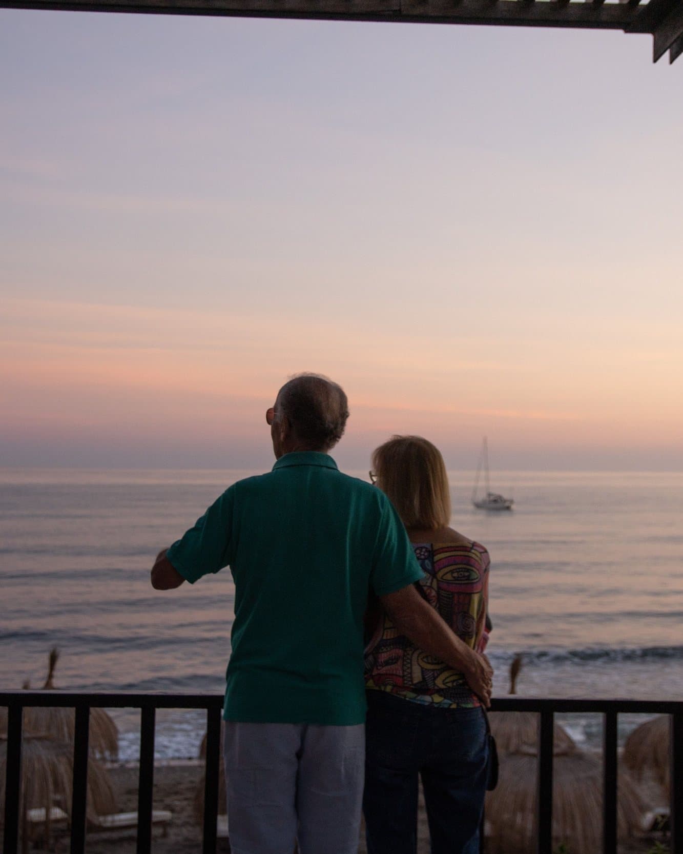 A couple on their terrace at dusk, looking out to sea
