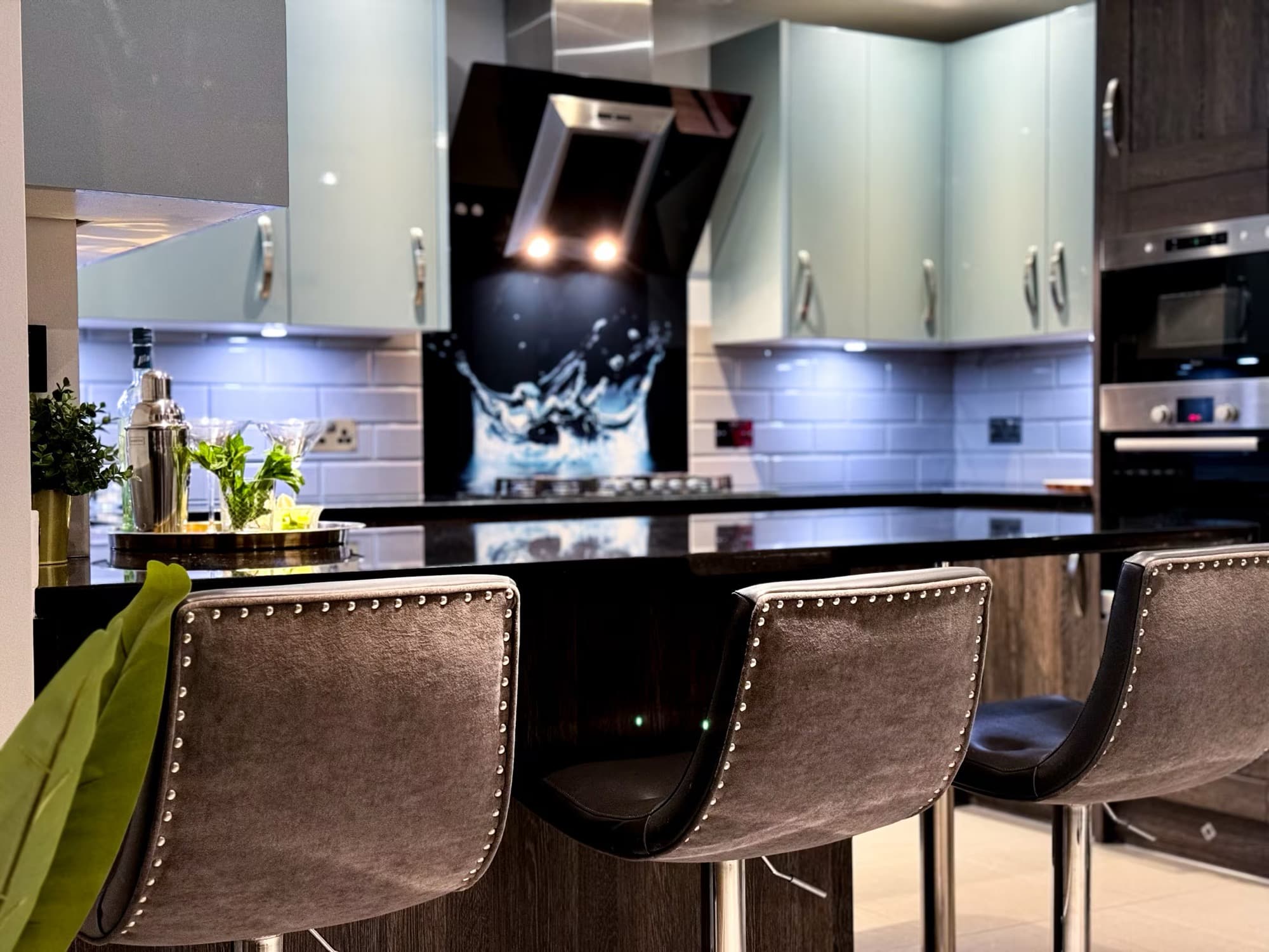 The kitchen in one of our London residences: a granite breakfast bar with stools, a gas hob and a built-in oven